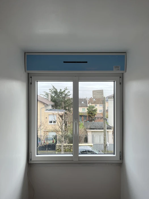 Fenêtre double battant en aluminium gris avec volet roulant bleu intégré au-dessus, installée dans un mur blanc