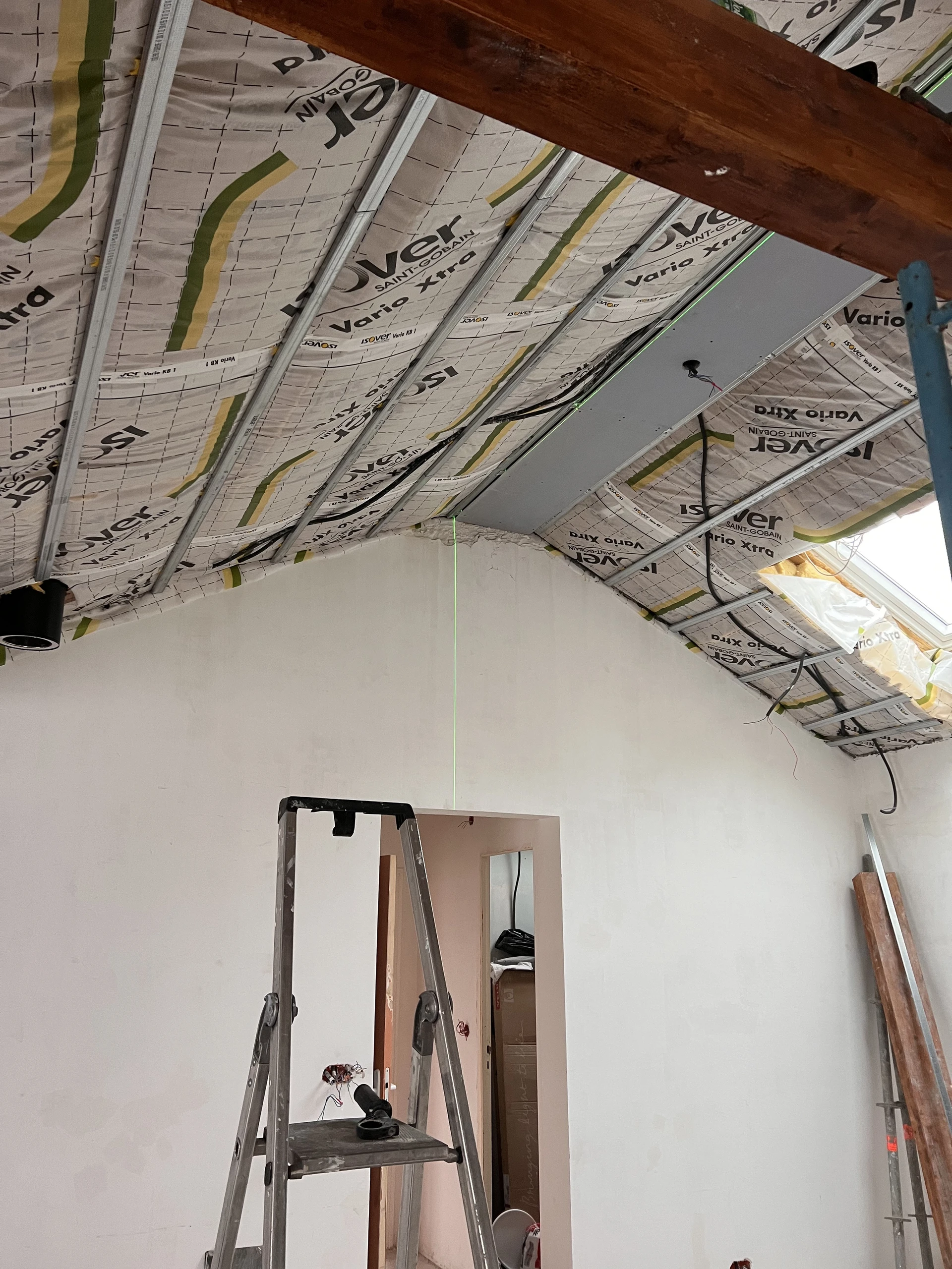 Chantier intérieur en cours de rénovation avec plafond ouvert exposant l'infrastructure électrique et les gaines techniques
