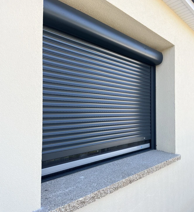 Volet roulant aluminium bleu et gris installé sur façade extérieure blanche