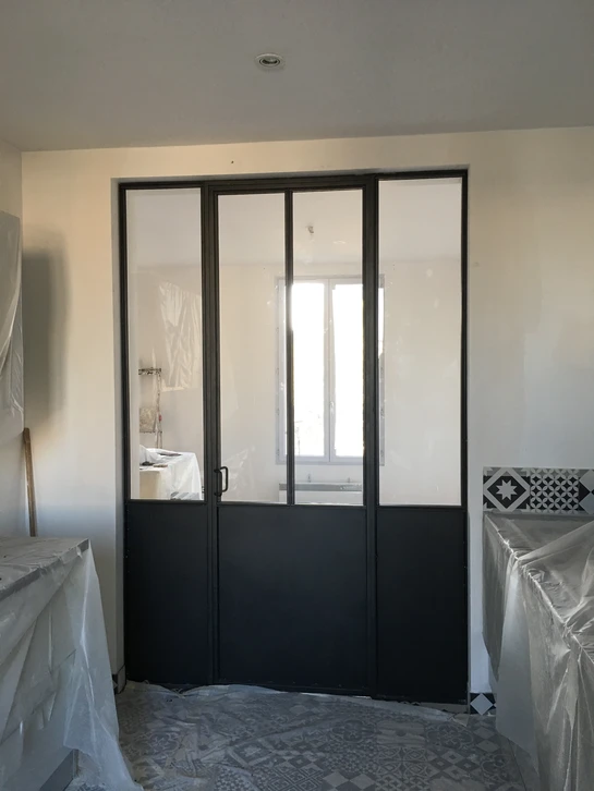 Intérieur contemporain séparé par une verrière coulissante à structure en acier noir
