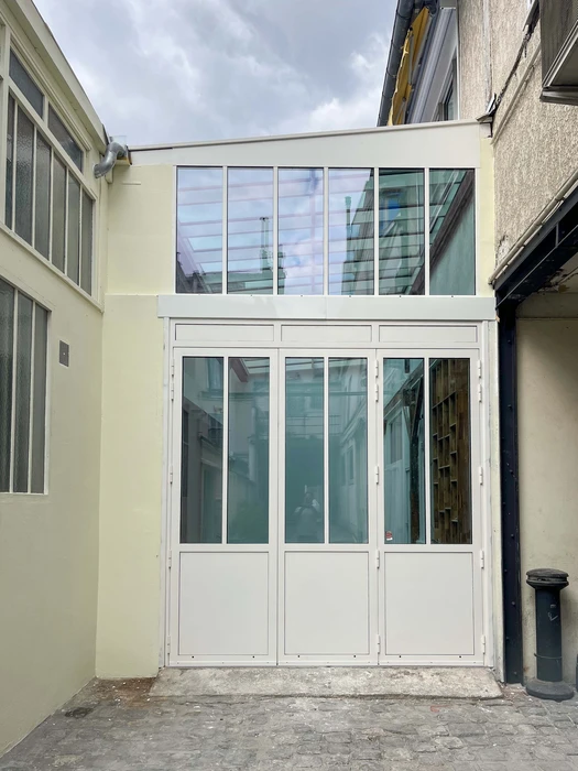 Terrasse extérieure avec bardage bois grisé et porte-fenêtre aluminium anthracite donnant accès à un intérieur lumineux